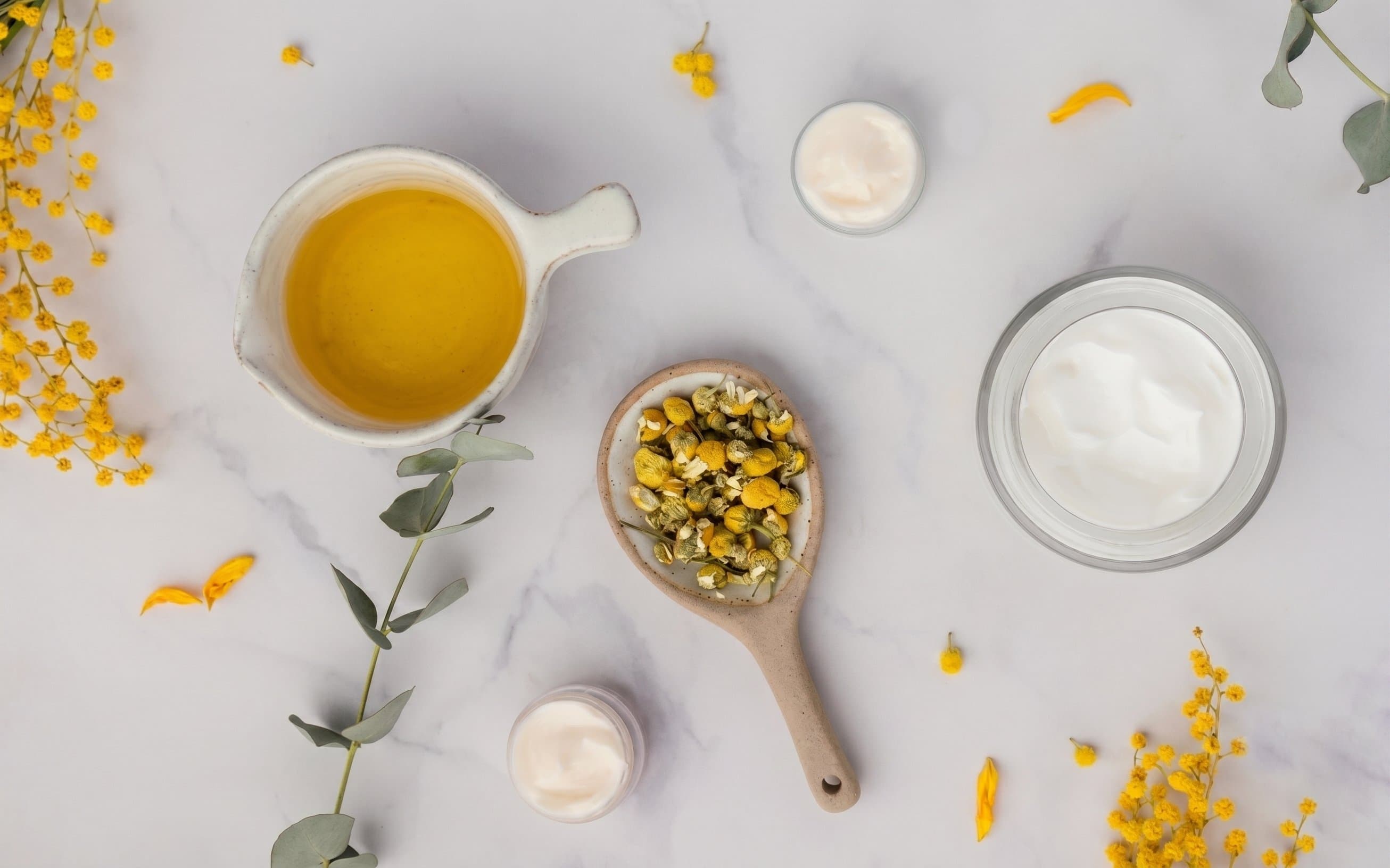 Skincare formulation flat lay with chamomile, botanical oil and cream textures